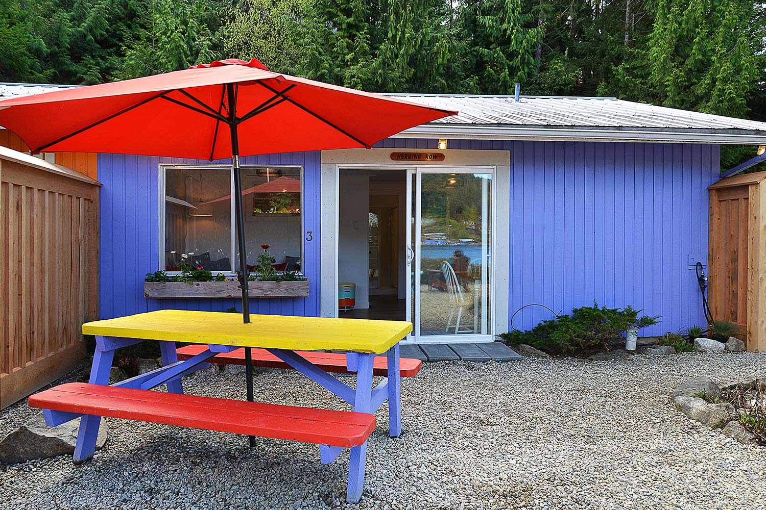 The front yard of Herring Row has a BBQ & picnic table. This purple cottage is one of 4 charming cottages at John Henry’s.