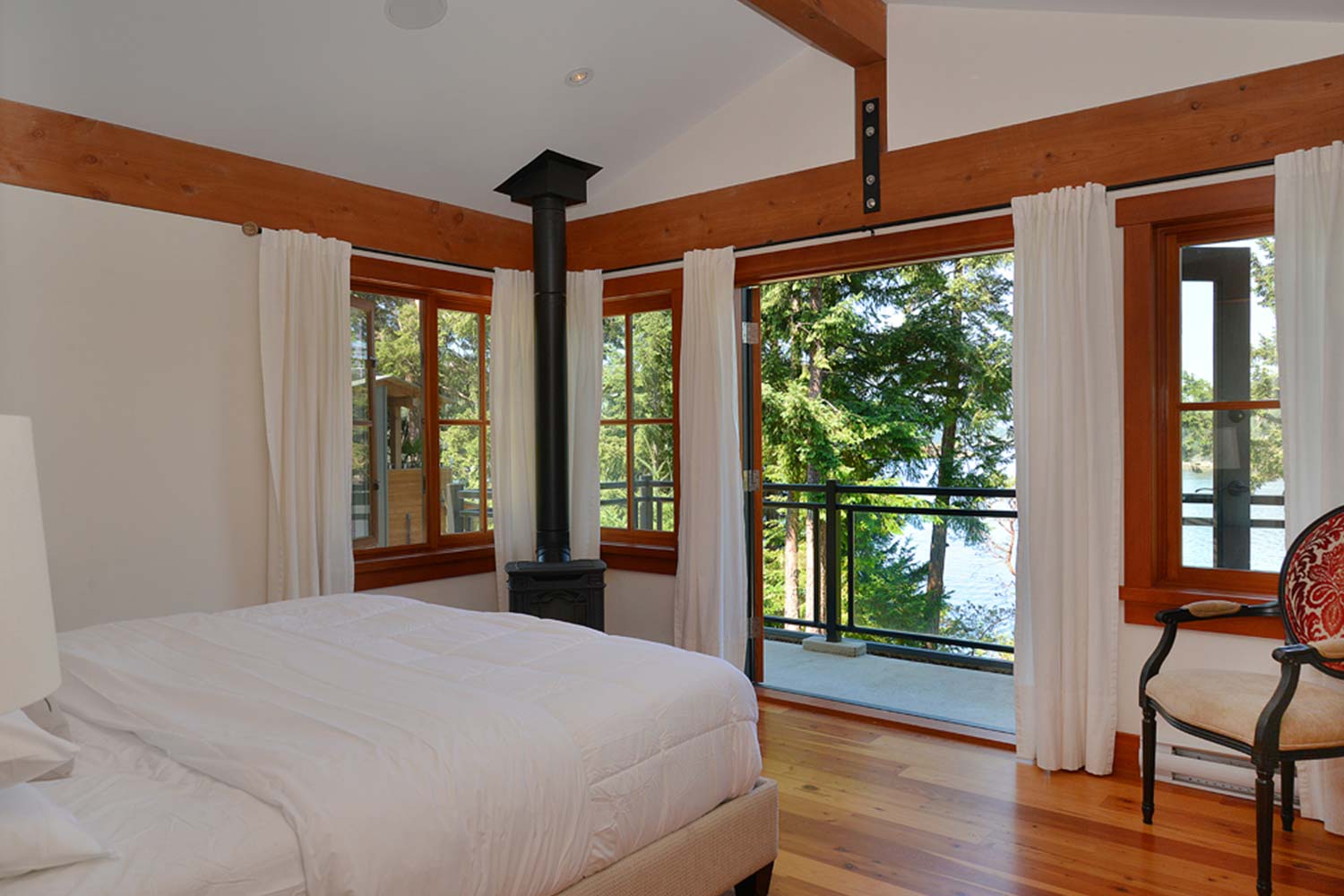 The upstairs master bedroom of this luxury holiday house features a private balcony with ocean views & a walk-in closet.