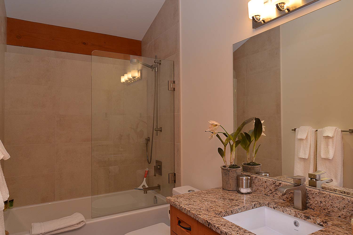 The bathroom of this home for rent by a private owner features a large shower/bath and granite-style countertop.