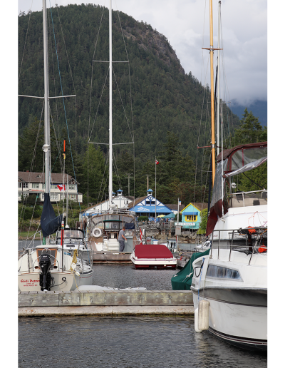 A view from the end of the dock of boats parked in the Marina and John Henry’s General Store in the background.