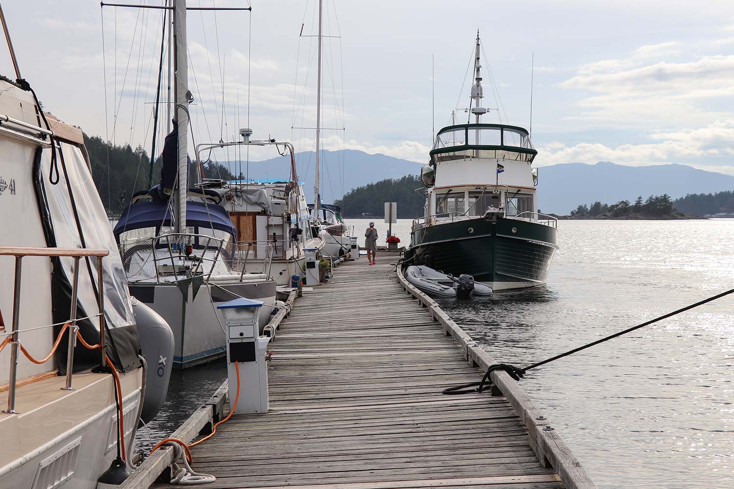 A lady walks down the dock, between several vessels parked at John Henrys Boat Moorage.